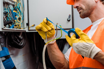 Canvas Print - Cropped view of electrician using insulating tape while fixing wires of electric panel