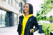 © My Ocean studio - Good walk with my smartwatch! A half-length photo of a young woman, dressed in leather jacket and yellow hoodie, enjoying her walk with her new smartwatch.