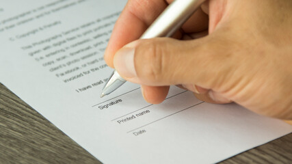 Wall Mural - A hand of a man signing a document. Hand holding a pen. 