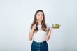 © ALEXSTUDIO - girl in a white t-shirt holds a bowl of salad in her hands and eats on a white background. Healthy Eating