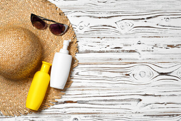 Wall Mural - Straw hat, sunglasses and sunscreen bottle on wooden background