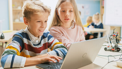 Wall Mural - brilliant schoolgirl and schoolboy talk and use laptop to program software for robotics engineering 
