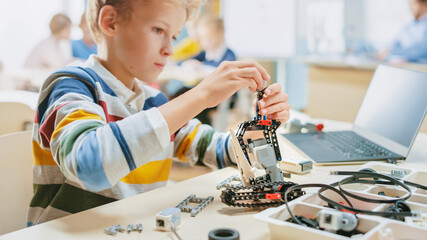 Wall Mural - schoolboy builds / constructs small robot and uses laptop to program software for robotics engineeri