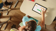 © Gorodenkoff - Top View Shot in Elementary School Computer Science Classroom: Children Sitting at their School Desk Using Personal Computers and Digital Tablets for Assignments.