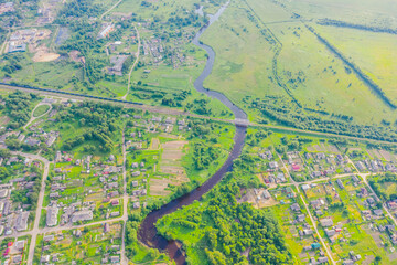 Wall Mural - Aerial view landscape of winding small river among the small town railway station and bridge, stream in green field, top view meadow.