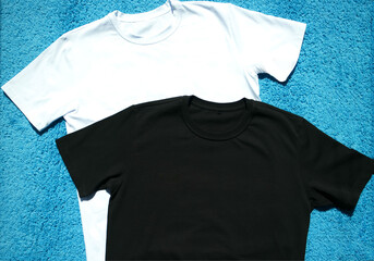 two T-shirts in black and white, on a hanger, neatly lie on a turquoise background, top view. Fashionable, modern, youth clothes. Clothing made from natural materials, cotton. Two t-shirts on a bright