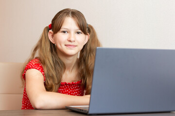 Distance learning online education. Little girl using laptop computer studying. Working at laptop and doing school homework.