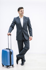 A young handsome businessman in a suit, comes with a suitcase, at the station, at the airport.