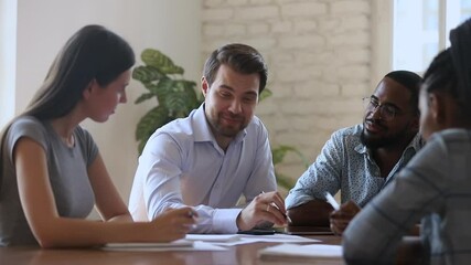 Canvas Print - Smiling male boss leader mentor and diverse business team laugh discuss paperwork planning project at group office briefing, happy multiracial staff talk work together joking sit at meeting table