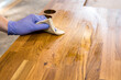 Person working, rubbing oiling with linseed oil natural wooden kitchen countertop before using. Solid wood butcher block countertop maintenance concept.