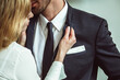 Young businesswoman holding jacket collar of businessman. Flirting couple of unrecognizable caucasian people. Passionate love affair in office workplace. Close up shot.