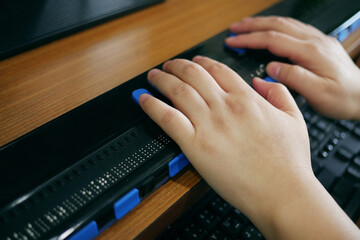 Close-up blind person woman hands using computer with braille display or braille terminal a technology assistive device for persons with visual disabilities.