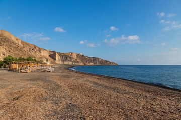 Kanakari beach on Santorini island in Greece. The background is a beautiful blue sky with white clouds.