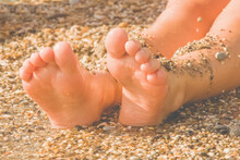 Vacation And Holidays Concept. Close Up Feet Of Young Girl Relaxing On Beach And Enjoying Sun And Sea On Sunny Summer Day.