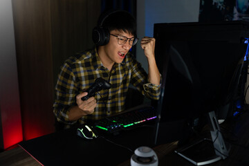 Asian man cyber sport gamer concentrated playing video games on computer eSport concept