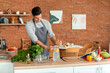 © Pixel-Shot - Young man with recipe book preparing fresh lemonade in kitchen