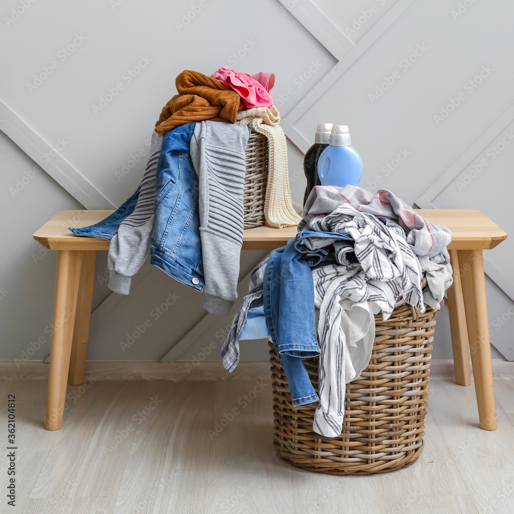 Baskets with dirty clothes on bench near light wall