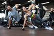 © ty - Strong man and woman holding dumbbells in plank position at the gym.