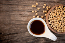 Tasty Soy Sauce And Soybeans In Ceramic And Wooden Bowl Isolated On Rustic Wood Table Background. Top View. Flat Lay.