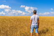 © Tatyana_Andreyeva - Adult tourist man admiring picturesque rural landscape of golden ripe rye field and blue sky in summer sunny day. Travelling to clean places of Earth or beauty of nature discovering concept