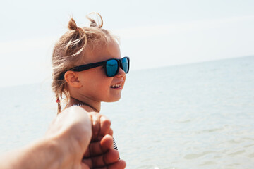 child pulls father to swim in the sea.