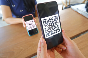 women's hand uses a mobile phone application to scan qr codes in stores that accept digital payments
