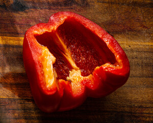 Sliced halves of sweet pepper lie on an oak board.