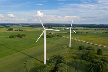 Aerial view of white wind turbines in green fields in summer