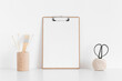 Wooden clipboard mockup with workspace accessories on a white table.