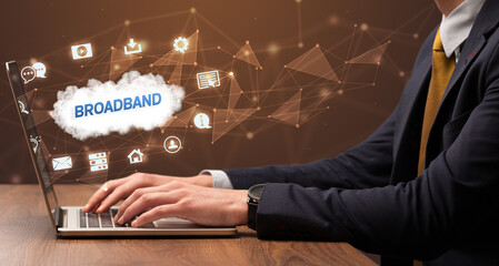 Businessman working on laptop with BROADBAND inscription, modern technology concept