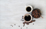 Fototapeta Tematy - Photo of coffee cups and coffee beans on light wooden background. Copy space for your text. Top view. Flat lay.