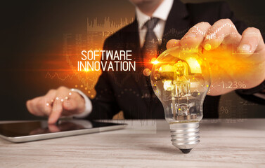 Businessman holding lightbulb with SOFTWARE INNOVATION inscription, Business technology concept