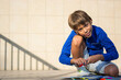© allai - The boy plays with felt-tip pens and books on the school porch