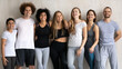 Group portrait of smiling beautiful multiracial diverse young people in sportswear embracing posing near wall, feeling excited of yoga morning routine workout in modern club, looking at camera.