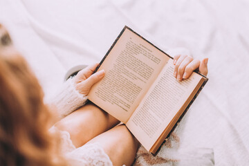 Wall Mural - Young woman on the bed with old book and cup of coffee enjoys her stay.