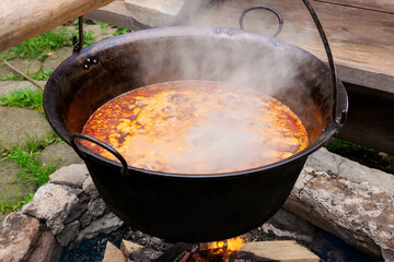 traditional hungarian bogracs goulash soup. cooking dish on open fire in a cauldron. preparing healthy food outdoors concept. popular european cuisine