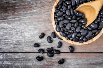 Wall Mural - Closeup black beans( Urad dal, black gram, vigna mungo ) in wooden bowl and scoop isolated on old rustic wood table background . Top view. Flat lay.