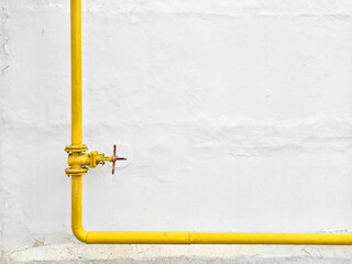 an iron pipe painted yellow against the white putty of an old wall