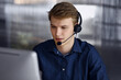 © rogerphoto - Young blond businessman using headset and computer at work. Startup business means working hard and out of time for success achievement