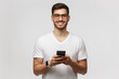 © Damir Khabirov - Portrait of young handsome man in white t-shirt and eyeglasses, standing with phone in hands, isolated on gray background