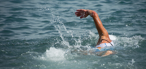 Wall Mural - Swim triathlete man swimming freestyle crawl in ocean, panorama