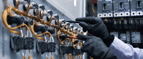 Fotomural Electrical engineer using digital multi-meter measuring equipment to checking electric current voltage at circuit breaker in main power distribution board