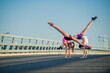 © Maria Moroz - Two teenage girls perform an acrobatic element outdoors against a blue sky