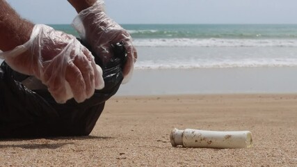 Canvas Print - Environmental issue: plastic bottles and trash pollute sea and beach. Volunteer picks up plastic garbage for recycling