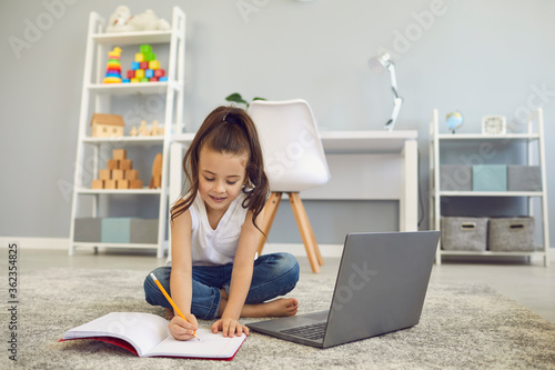 Online education of children. A little girl does a teacher lesson from a video lesson a distance learning web conference at home.