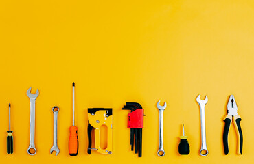 Wall Mural - Tools top view on yellow background. Plier, open wrenches, screwdrivers and staple gun flat lay with copy space.