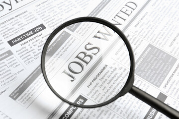 Wall Mural - Looking through magnifying glass at newspaper, closeup. Job search concept