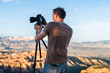 © Kristina Blokhin - Man taking pictures photos of view from Bryce Point overlook of hoodoos rock formations in Bryce Canyon National Park at sunset with tripod and camera