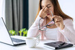 © Kittiphan - Tired and stressed young asian woman feel pain eyestrain and rubbing her eyes and take off her glasses while sitting at her working place