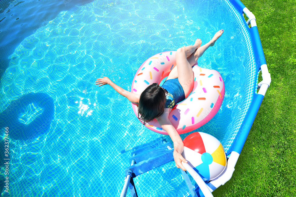 Pool time. Girl has fun in a summer metal frame pool. - obrazy, fototapety, plakaty 